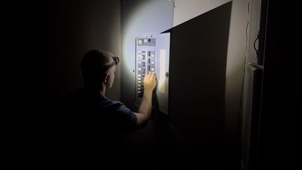 Austin Monday working on an electrical panel by headlamp during an emergency call